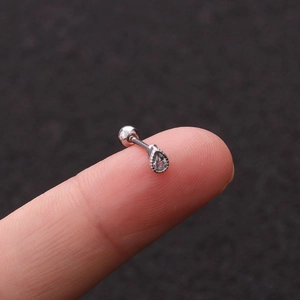Close-up of a tiny silver drop-shaped stud earring with zircon on a fingertip