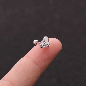 Macro shot of a silver heart stud earring with cubic zirconia on a fingertip