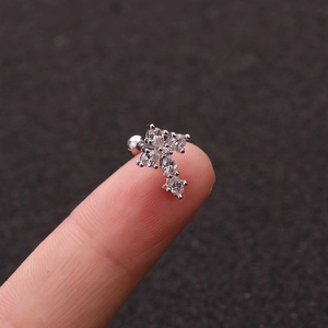 Close-up of a silver butterfly stud earring with clear zircon inlay on a finger