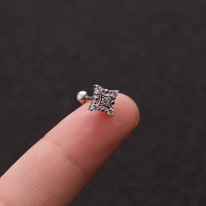 Macro shot of silver square stud earring with clear zircon held by fingers