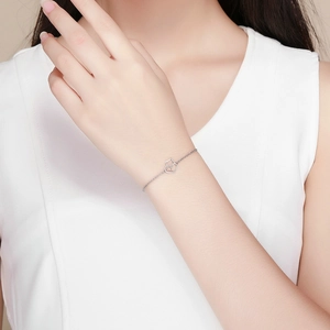 Dettaglio del bracciale in argento S925 con ciondoli a gatto e cuore indossato al polso