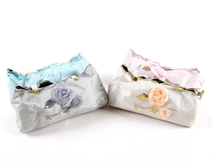 Detail of embroidered fabric storage cases with 3D roses in blue, grey, pink, and beige