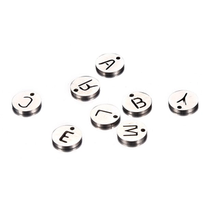 Polished stainless steel round alphabet pendants with engraved letters on white background