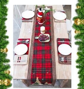 Close-up of red and black plaid Christmas table runner set with festive embroidery detail