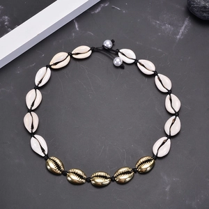 Natural pearl shell necklace with gold accents on a black cord over marble background