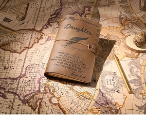 Close-up of vintage brown leather journal with engraved father to daughter message