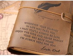 Close-up of vintage brown leather notebook with embossed emotional quote and elastic strap