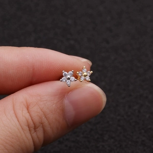 Macro detail of small flower stud earrings with zircons in gold and silver finish