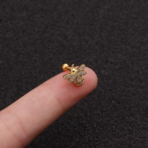 Mini gold bee stud earring with sparkling cubic zirconia held on a fingertip