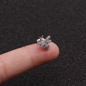 Mini bee stud earring in stainless steel with sparkling cubic zirconia on a finger