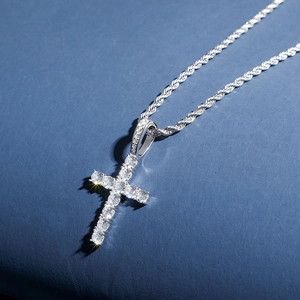 Macro shot of silver cross pendant with clear cubic zirconia on a twisted rope chain