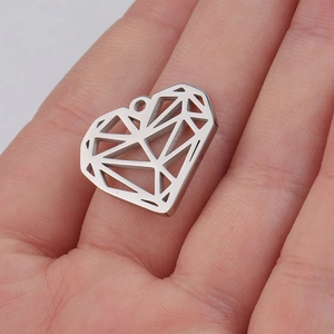 Hand holding a silver stainless steel hollow heart pendant with geometric faceted design