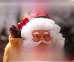 Detail of Christmas Santa ornament with plush beard, pine cones and golden gift box accessory