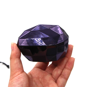 Macro detail of dark purple gem-shaped foundation brush case held by a hand