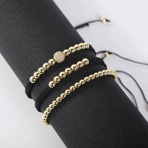 Detailed view of three adjustable braided gold bead bracelets with micro-pave zircon charms