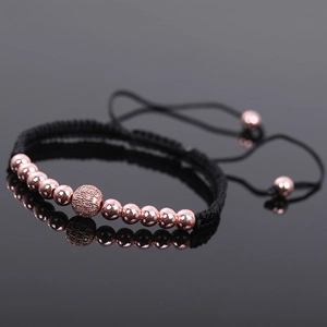 Macro shot of rose gold beads and zircon ball on an adjustable black braided bracelet