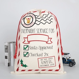 Close-up of cream canvas Christmas gift bag with red drawstring and festive Santa typography