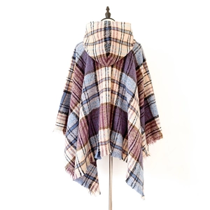 Dettaglio di poncho con cappuccio a quadri e frange in viola e blu su manichino