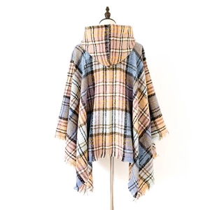 Dettaglio di un poncho con cappuccio a quadri multicolore con nappe in rosa e blu
