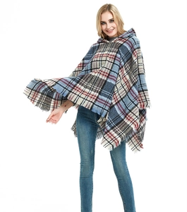 Dettaglio del poncho con cappuccio a quadri blu e rossi con frange e tessuto drappeggiato