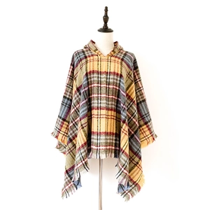 Dettaglio di un poncho con cappuccio a quadri colorati e frange su un manichino