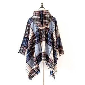 Dettaglio del poncho con cappuccio a quadri blu e viola e bordi rifiniti con frange