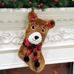 Chaussette de Noël ours brun avec écharpe à carreaux suspendue à une cheminée blanche