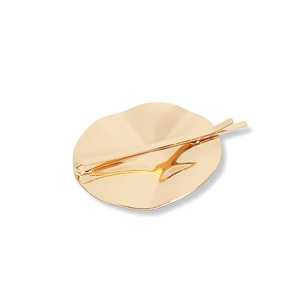 Minimalist golden metal hair clip with a round textured geometric relief pattern