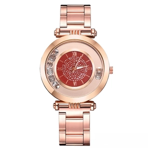 Détail de montre femme or rose avec cadran rouge scintillant et strass mobiles