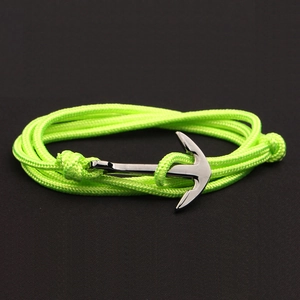 Detail of neon green multi-wrap nylon rope bracelet featuring a silver anchor charm