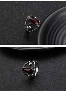 Macro shot of silver skeleton hands holding a red coffin gem on a gothic punk ring