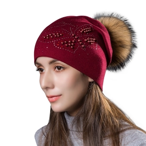 Bonnet en tricot bordeaux avec pompon en fourrure, perles et strass sur fond blanc
