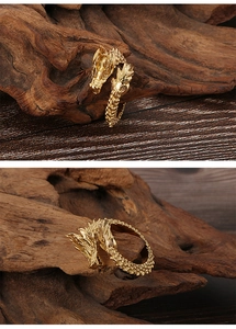 Detail view of golden dragon head ring with intricate scales on dark wood background