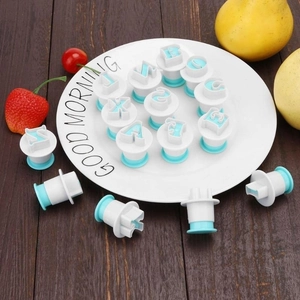 Detail of spring-loaded letter fondant stamps with fruit accents on a rustic wooden table