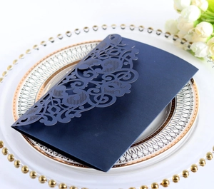 Close-up of a laser-cut navy blue wedding invitation envelope on a decorative plate