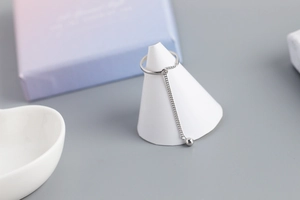 Detail of S925 sterling silver chain tassel ring with a small zircon stone on a stand