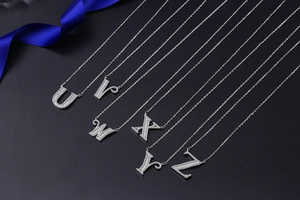 Detailed close-up of diamond-encrusted U-Z letter pendants on delicate chain necklaces