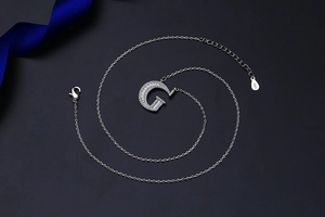 Macro shot of S925 silver clasp and letter G pendant with cubic zirconia stones