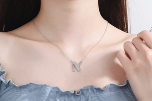 Close-up of sparkling silver letter N pendant necklace with diamonds on a model