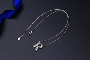 Macro detail of S925 sterling silver letter R pendant with sparkling pavé zircons