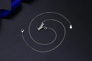 Detail of silver letter Y pendant necklace with pavé zircon stones on black background