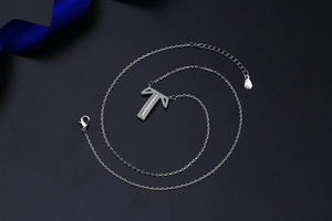 Macro detail of silver S925 letter T pendant with pavé cubic zirconia on cable chain
