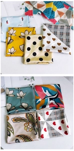 Flat lay of small silk scarves with various geometric and floral patterns on white background