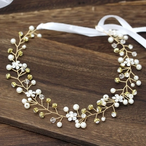 Detail of bridal headband with pearls, rhinestones, white flowers and ribbons on wood