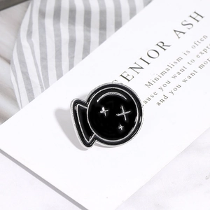 Macro shot of a black enamel round brooch with silver cross stars on a white card