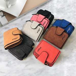 Flat lay of multiple colorful matte leather wallets with snap buttons on marble surface