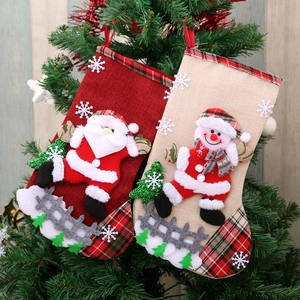 Red and beige linen Christmas stockings with Santa and Snowman hanging on a tree