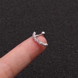 Macro shot of curved silver stainless steel ear stud with inlaid cubic zirconia crystals