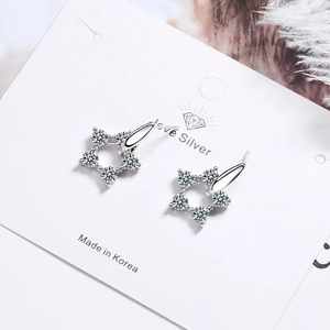 Sparkling silver star-shaped earrings with zircons displayed on a white jewelry card