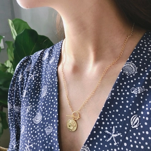 Detail of 925 sterling silver gold coin pendant necklace with OT toggle clasp on model
